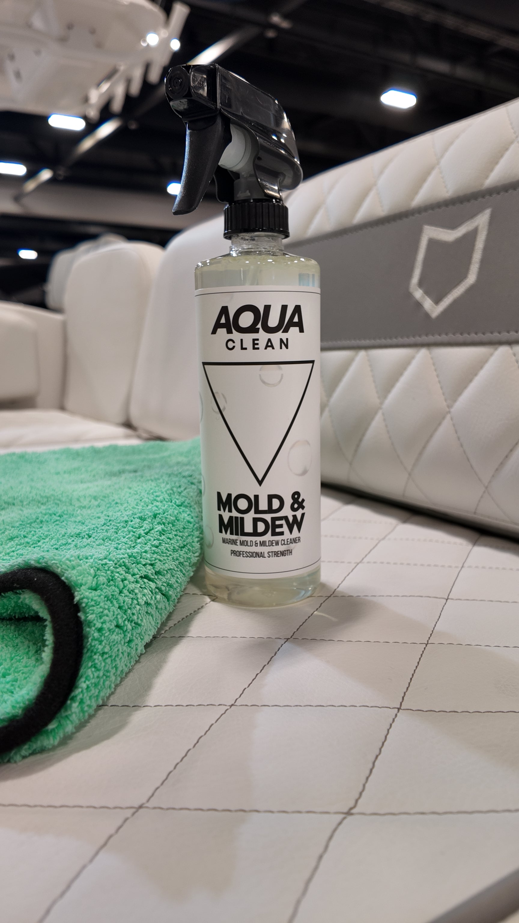 AquaClean Mold and Mildew cleaner bottle on tiled floor with green rug and white furniture in background